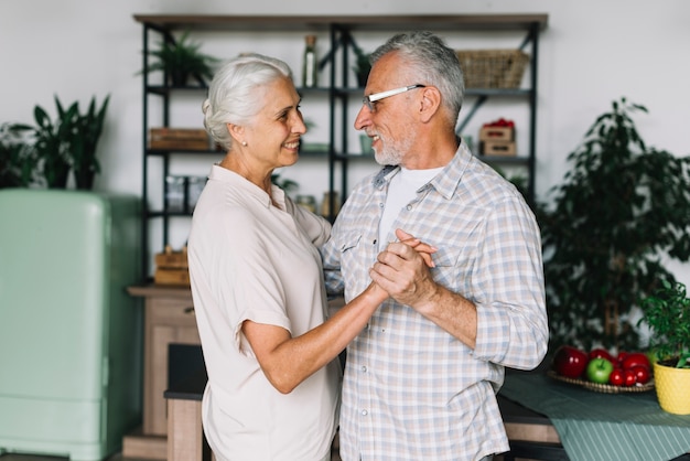 Smiling senior couple dancing in the kitchen