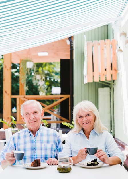 Coppie senior sorridenti che si siedono in caffè sul terrazzo