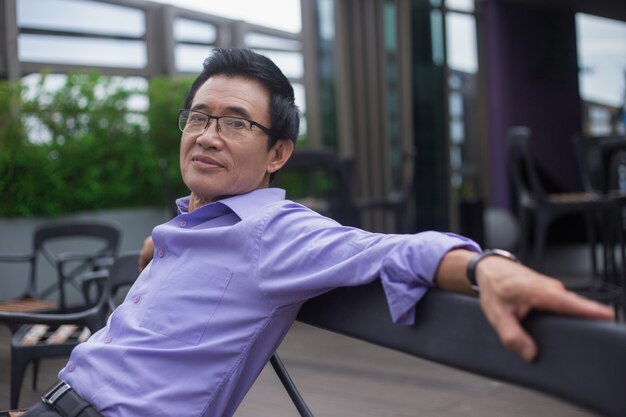 Smiling Senior Man Resting on Bench in Cafe