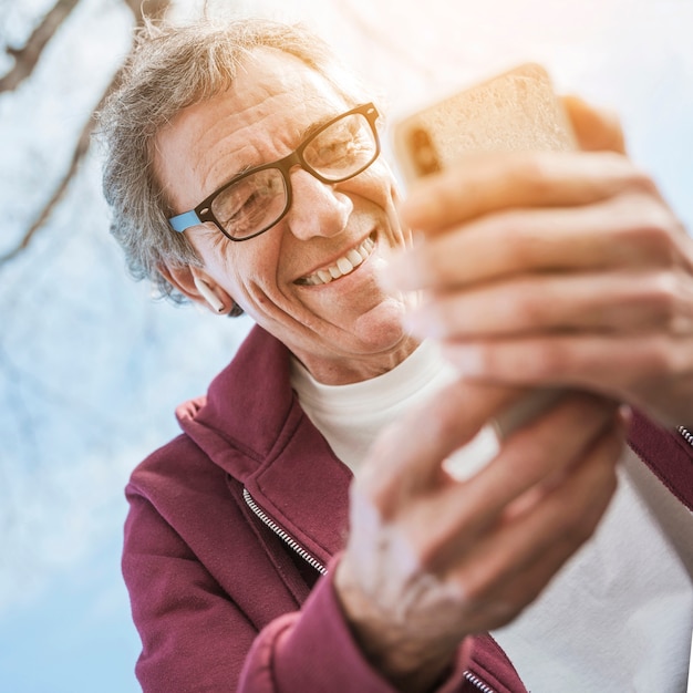 スマートフォンを使って眼鏡をかけている笑顔の高齢者