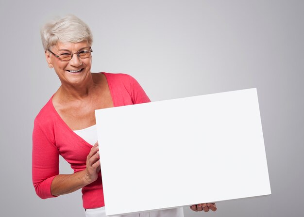 ホワイトボードを持って笑顔の年配の女性