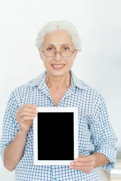 Foto gratuita occhiali d'uso sorridenti della donna senior che mostrano compressa digitale con lo schermo in bianco