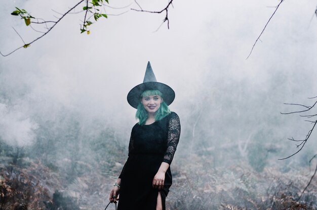 Smiling sensual witch walking in smoke