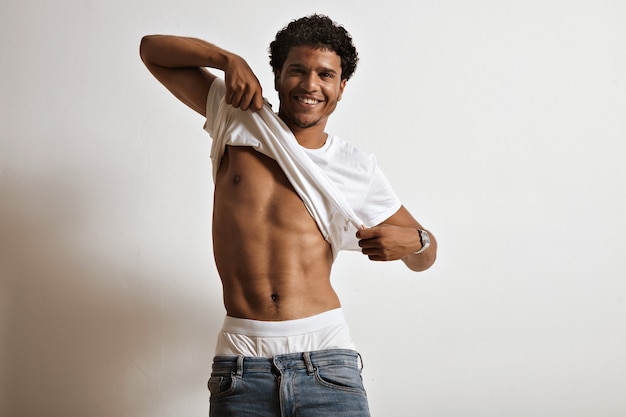 Free photo smiling sexy black model raising his white unlabeled t-shirt showing beautiful abs and white underwear