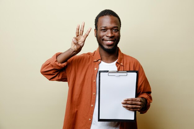 白い背景で隔離のクリップボードを保持している若いアフリカ系アメリカ人男性の数を示す笑顔