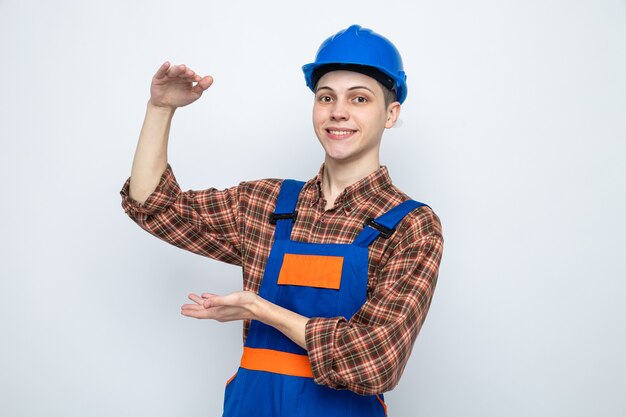 Smiling showing size young male builder wearing uniform 