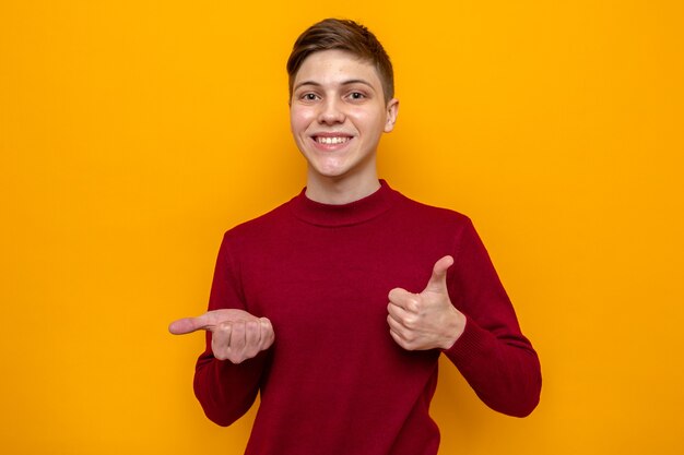 Smiling showing thumb up young handsome guy wearing red sweater 