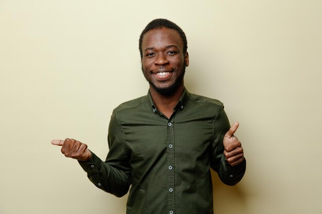緑のシャツを着て若いアフリカ系アメリカ人男性が白い背景で隔離の親指を見せて笑顔