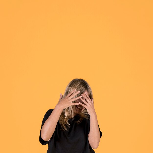 Smiling shy woman covering her face with finger