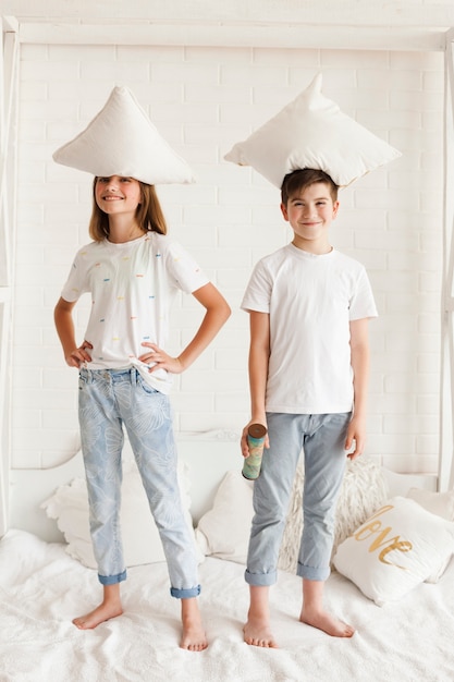 Smiling sibling standing with pillow on their head in bedroom