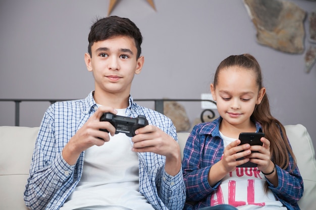 Smiling siblings with smartphone and controller