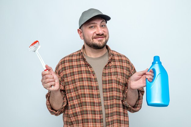 Smiling slavic cleaner man holding toilet cleaner liquid and brush