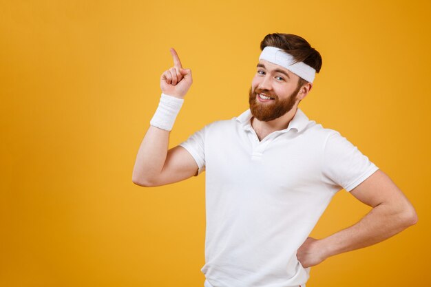 Smiling sportsman holding arm at hip and pointing up