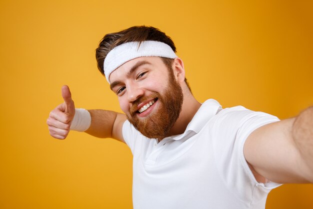 Smiling sportsman making selfie and showing thumb up