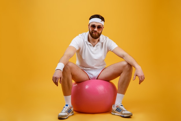 Улыбающийся спортсмен, сидя на фитнес-мяч