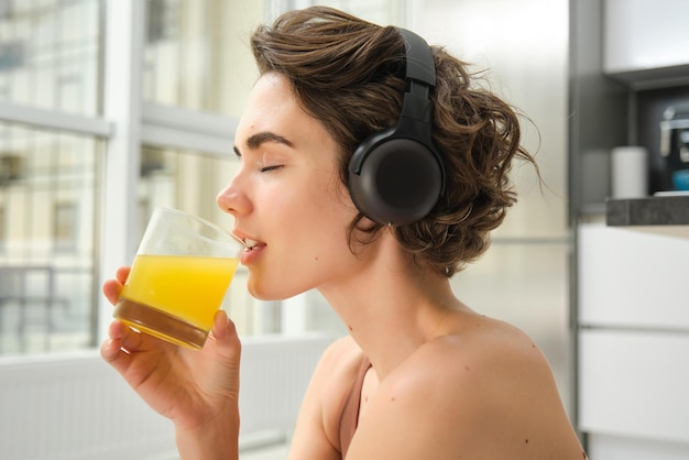 smiling-sportswoman-fitness-girl-does-workout-home-wears-headphones-listens-music-drinks-oran_1258-183868.jpg