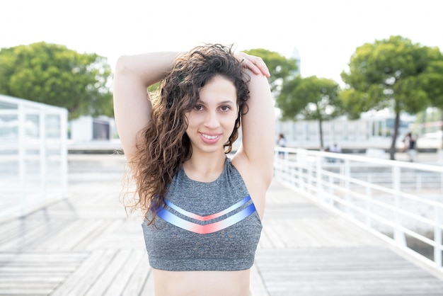 Free photo smiling sporty girl stretching arm on bridge