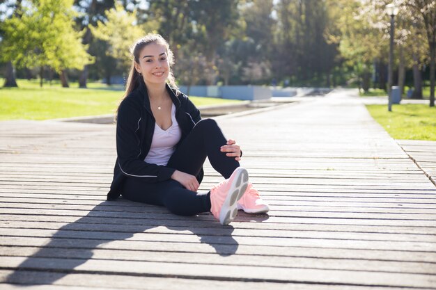 Smiling sporty lady relaxing in city park