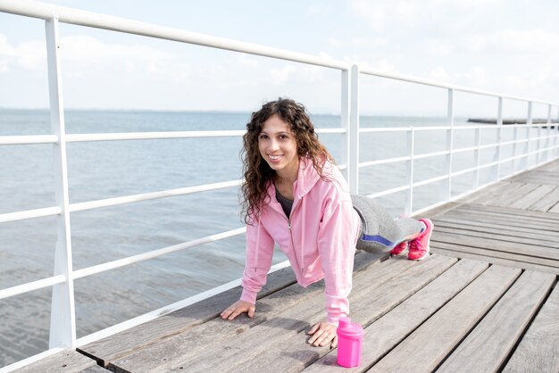 Smiling Sporty Woman Doing Plank on Wooden Bridge
