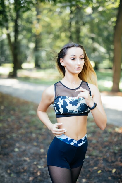 Smiling sporty young woman running outdoors in park