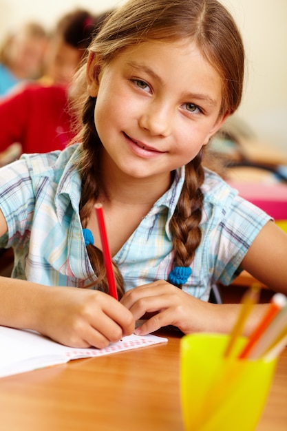 Smiling student holding a red pencil