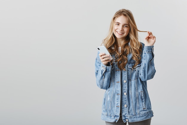 스마트 폰 앱을 사용하여 온라인 쇼핑을 웃는 세련된 금발 소녀