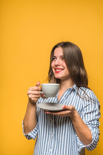 グレーのカップでコーヒーを飲んで笑顔のスタイリッシュな若い女性