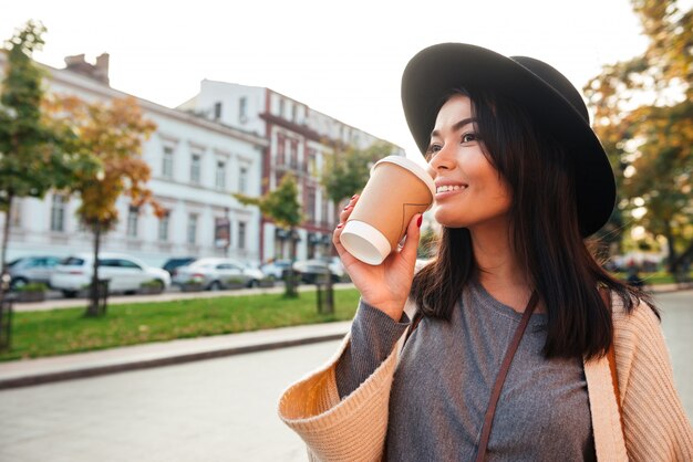 コーヒーを飲んで笑顔のスタイリッシュな若い女性