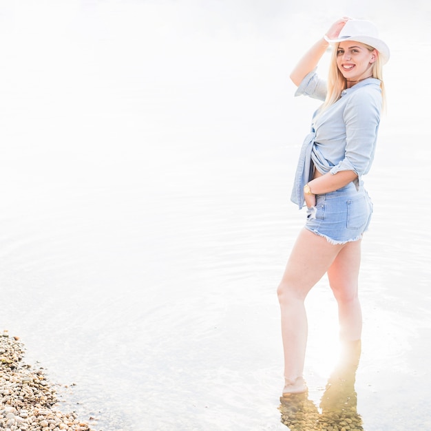 Giovane donna alla moda sorridente che sta nel lago