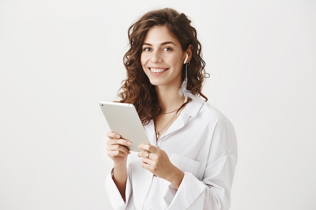 디지털 태블릿 무선 이어폰에 성공적인 여성 기업가 미소