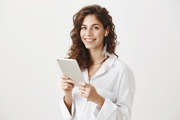 デジタルタブレットとワイヤレスイヤホンで成功した女性起業家を笑顔
