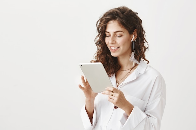 Sorridente imprenditore femminile di successo in auricolari wireless con tavoletta digitale
