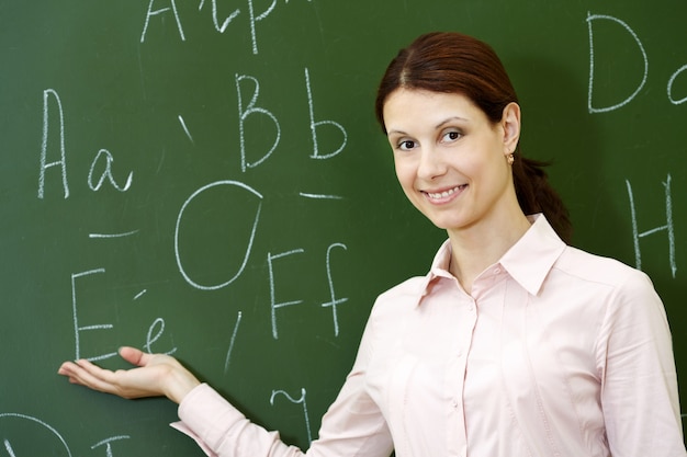 Free photo smiling teacher with blackboard background