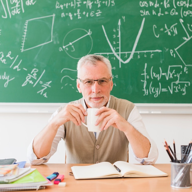 Smiling teacher with drink in classroom