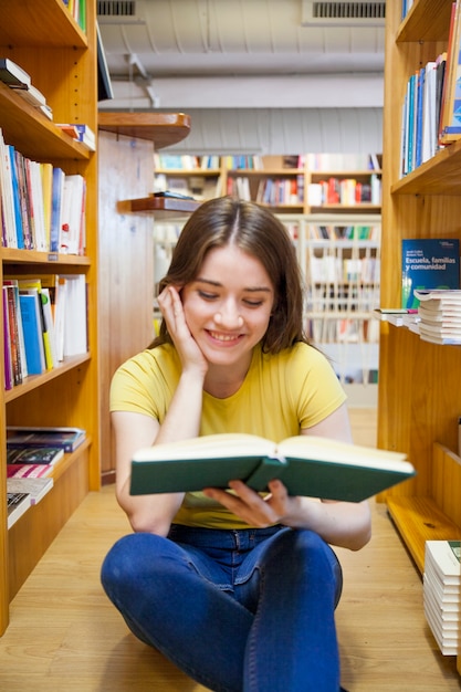 Foto gratuita sorridente ragazza adolescente godendo la lettura sul pavimento