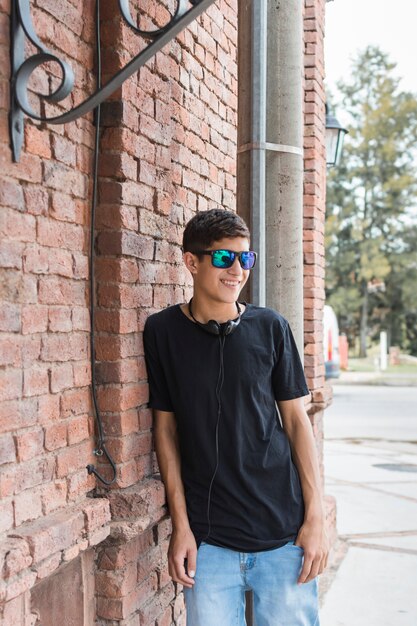 Smiling teenage boy leaning on brick wall