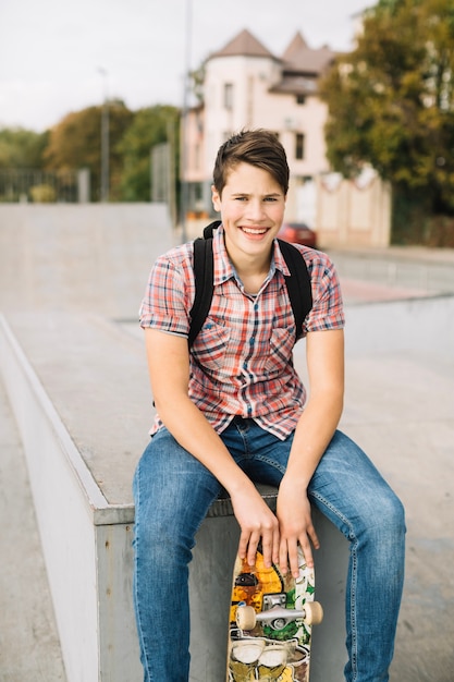 Foto gratuita adolescente sorridente che si siede con il pattino