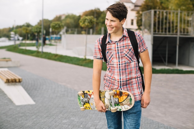 Бесплатное фото Улыбаясь подросток ходить с скейтборд