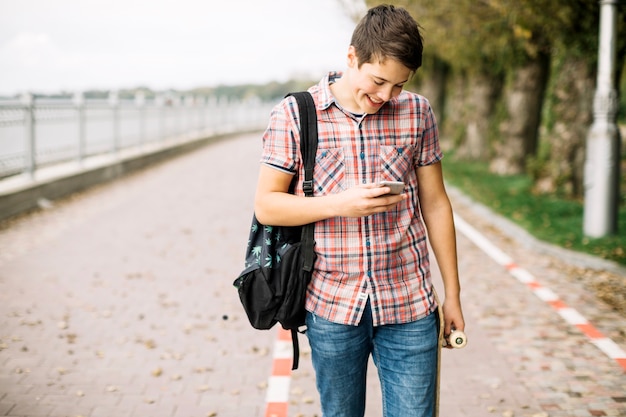 Smiling teenager with skateboard using skateboard