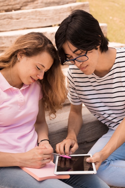 Free photo smiling teenagers surfing internet on tablet on stairs