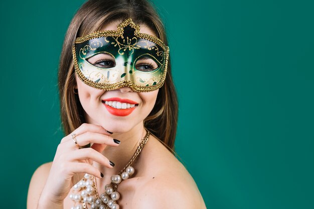 Smiling topless woman wearing masquerade carnival mask and necklace