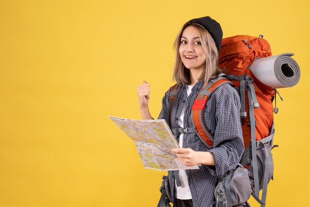 smiling traveller woman with backpack holding map pointing at