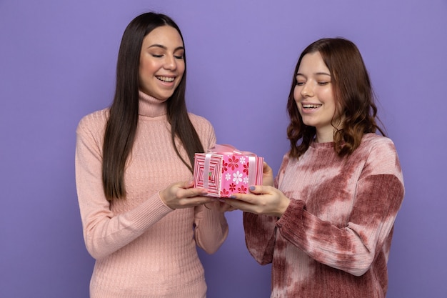 Smiling two girls holding and looking at gift box
