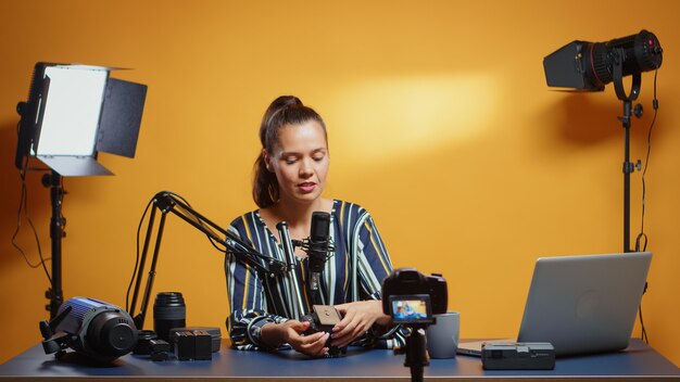 Smiling videography expert showing to the camera ways to mount fluid head plate. Influencer making online internet content about video equipment for web subscribers and distribution, digital vlog talk