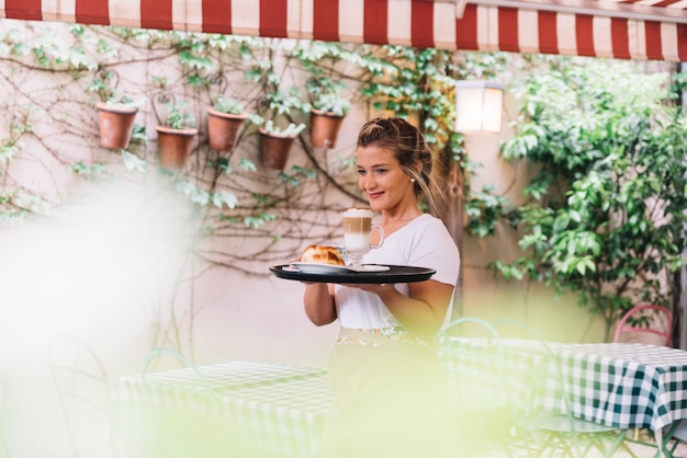 Free photo smiling waitress holding tray