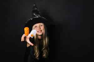 Free photo smiling witch showing halloween toys