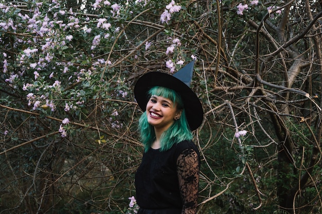 Free photo smiling witch at tree with flowers