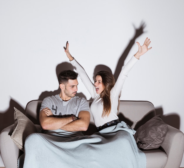 Free photo smiling woman and angry man watching tv on sofa