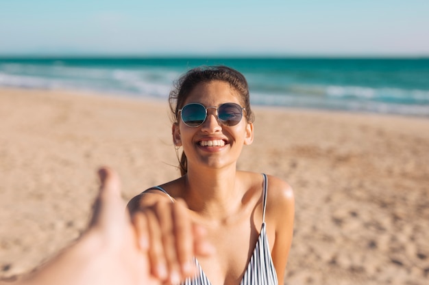 Smiling woman on beach holding hand 