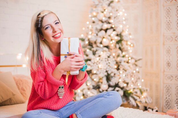 Smiling woman on bed with gift box